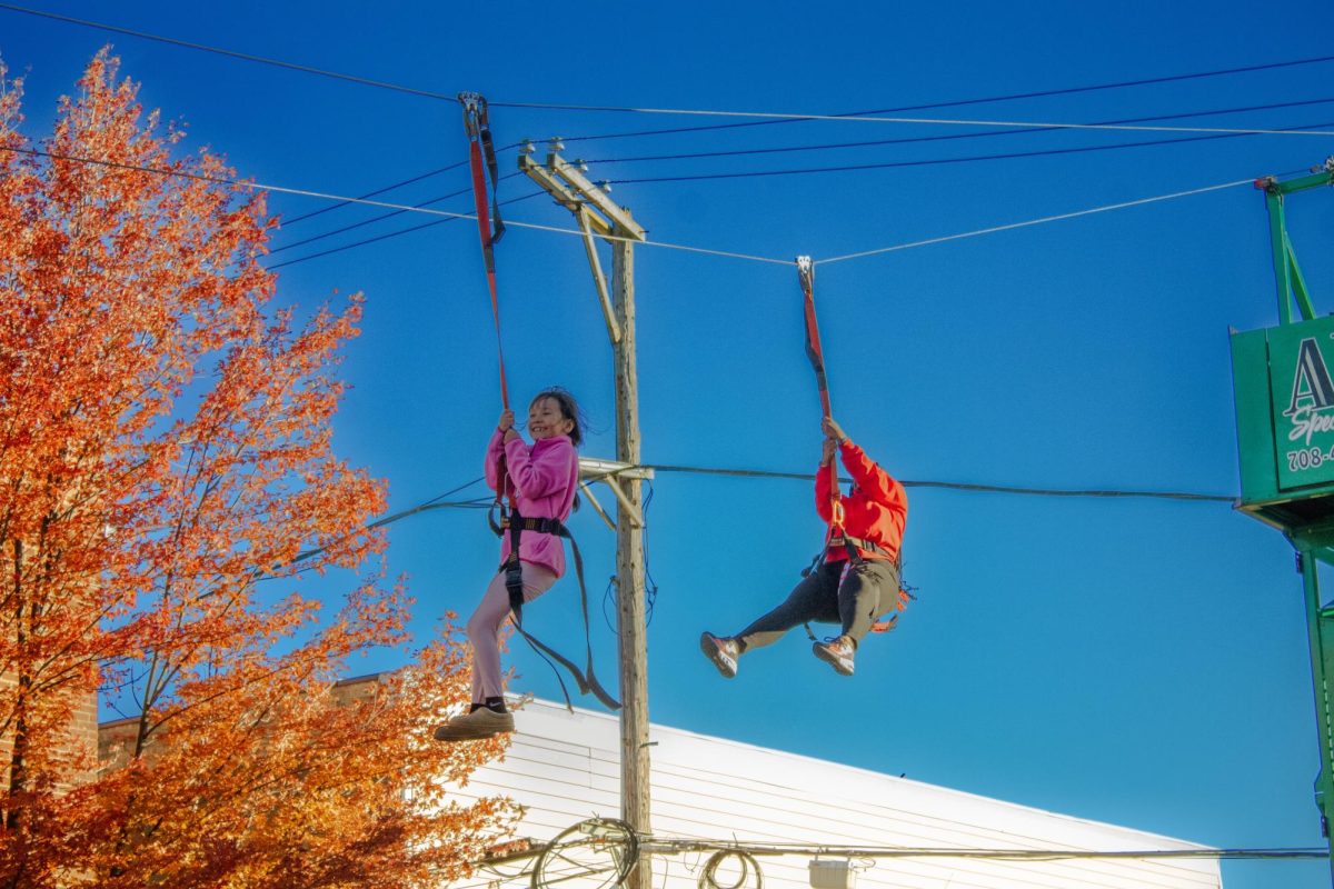 Aviane Marrufo (left), daughter of Carmesha Hicks, complex coordinator of Neptune and Gilbert Residence Halls, zip lines down Second Street during the Homecoming Block Party of Fall 2024. The Homecoming Block Party will return in 2025 from 5 p.m. to 8 p.m. on Thursday from the 100 to 400 block of East Lincoln Highway. (Northern Star File Photo)