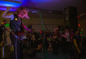 JM Graveside, bassist of Kozmic Kicks, raises his arm mid-riff as a crowd dances at Fargo during the 7–10 p.m. show, which featured four local bands. The bands played covers from Nirvana, Chevelle, and Deftones alongside original tracks. (Brynn Krug | Northern Star)