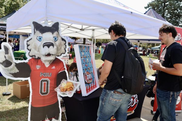 (From left) Sophomore electrical engineering majors Rafael Pineda and Luis Solis play a game of plinko at the Raising Canes table at the NIU Involvement Fair. Several businesses that tabled at the Involvement Fair on Wednesday offered coupons to students. (Sofia Howell | Northern Star) 