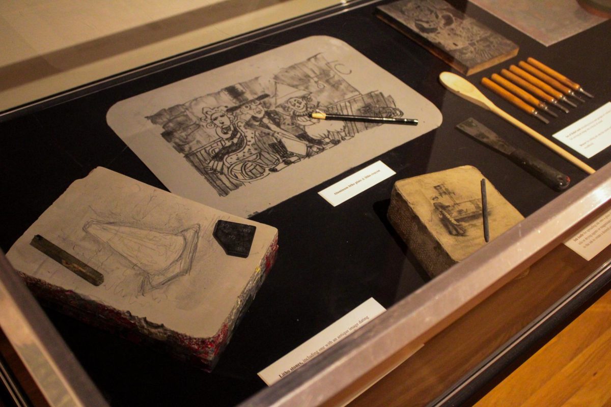 Several litho stones and pencils sit in a large glass display case at the “60 Years of NIU Printmaking” exhibit in Altgeld Hall. Litho stones were used between 1850 to 1920 for commercial printing and were replaced with zinc due to being much cheaper and lighter. (Ethan Rodriguez | Northern Star)