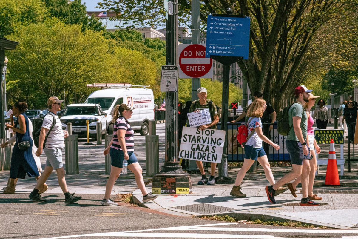 A photo depicts a person holding a sign that says "Stop starving Gaza's children" on Sept. 5 while people walk across the street in Washington, D.C. Opinion Columnist Ethan Ernst argues that too many innocent people will die if Israel goes all in on destroying Hamas. (Totus Tuus Keely | Northern Star)