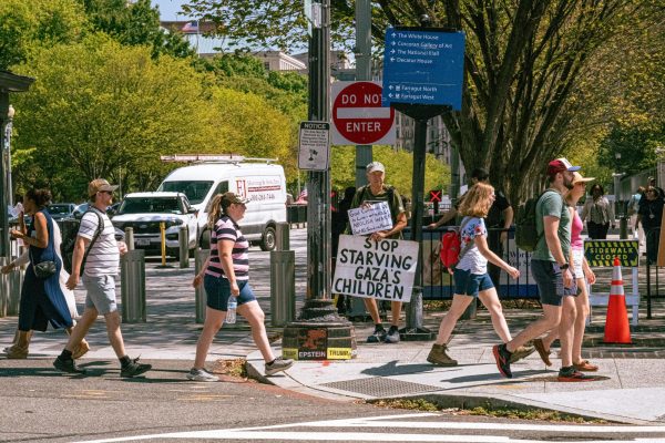 A photo depicts a person holding a sign that says "Stop starving Gaza's children" on Sept. 5 while people walk across the street in Washington, D.C. Opinion Columnist Ethan Ernst argues that too many innocent people will die if Israel goes all in on destroying Hamas. (Totus Tuus Keely | Northern Star)