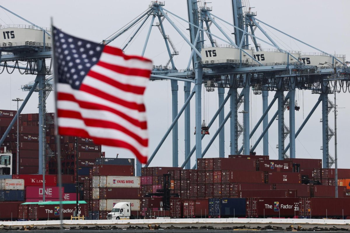 A U.S. flag flutters in front of shipping containers at the Port of Long Beach in Long Beach, California. Opinion Columnist Ethan Ernst believes that America needs to embrace that trading goods makes the U.S. stronger. (REUTERS | Daniel Cole)