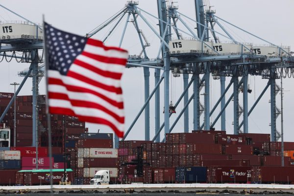 A U.S. flag flutters in front of shipping containers at the Port of Long Beach in Long Beach, California. Opinion Columnist Ethan Ernst believes that America needs to embrace that trading goods makes the U.S. stronger. (REUTERS | Daniel Cole)