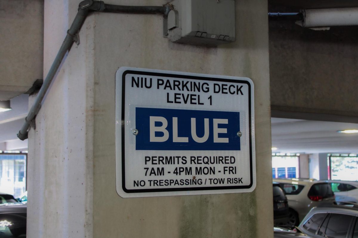 Blue parking sign sits on a pilar in the first level of the NIU Parking Garage. The Northern Star Editorial Board believes that students who live close to the campus should walk or take the bus to free up parking spots for students who live further away. (Ethan Rodriguez | Northern Star)
