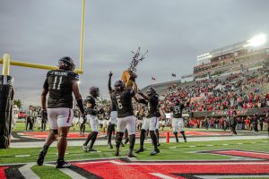 NIU senior defensive tackle Dasean Dixon (6) hoists the Bronze Stalk trophy as his teammates join him to celebrate the Huskies' 21-7 win over archrival Ball State University on Saturday at Huskie Stadium in DeKalb. The victory snapped NIU's six-game losing streak and its three-game skid in the all-time series against Ball State, which the Huskies now lead 26-25-2. (Totus Tuus Keely | Northern Star)