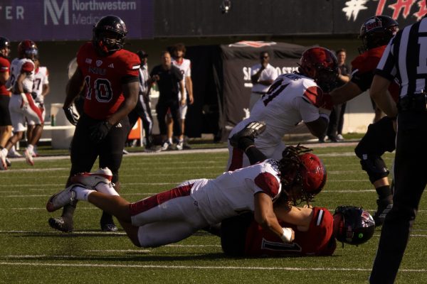 NIU redshirt senior running back Chavon Wright (10) looks on as redshirt sophomore quarterback Josh Holst, bottom, is sacked by San Diego State University sophomore linebacker Owen Chambliss during a football game on Sept. 27 at Huskie Stadium in DeKalb. NIU's 6-3 loss to San Diego State was the third among the Huskies' ongoing six-game losing streak. (Alexia Beck | Northern Star)