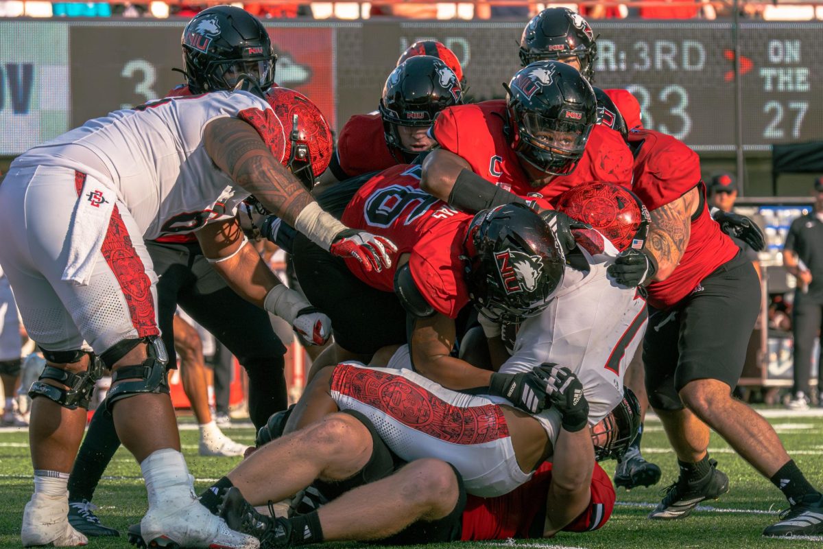 NIU redshirt sophomore defensive end Jay’shon Thomas (16), redshirt senior defensive end Jalonnie Williams and redshirt sophomore defensive tackle Mark Hensley, bottom, tackle San Diego State University junior running back Lucky Sutton (7) during the third quarter of a football game on Sept. 28 at Huskie Stadium in DeKalb. The Huskies will play the Ohio University Bobcats on Saturday at Peden Stadium in Athens, Ohio. (Totus Tuus Keely | Northern Star)
