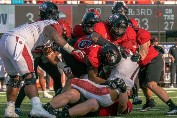NIU redshirt sophomore defensive end Jay’shon Thomas (16), redshirt senior defensive end Jalonnie Williams and redshirt sophomore defensive tackle Mark Hensley, bottom, tackle San Diego State University junior running back Lucky Sutton (7) during the third quarter of a football game on Sept. 28 at Huskie Stadium in DeKalb. The Huskies will play the Ohio University Bobcats on Saturday at Peden Stadium in Athens, Ohio. (Totus Tuus Keely | Northern Star)