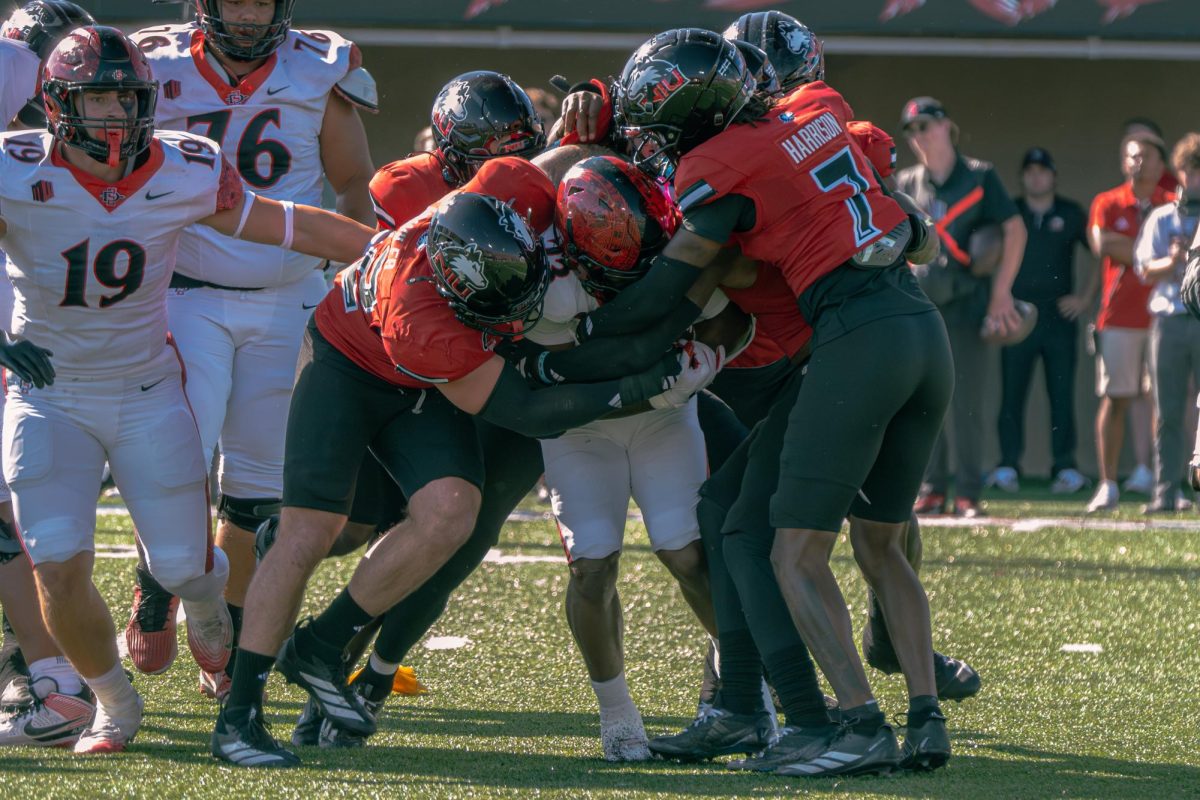 NIU defensive players wrap up San Diego State University junior running back Christian Washington (23) for a tackle for loss during the first quarter of Saturday's football game at Huskie Stadium in DeKalb. The Huskies received a 70.6 overall defense grade from Pro Football Focus after a 6-3 loss to the Aztecs. (Totus Tuus Keely | Northern Star)