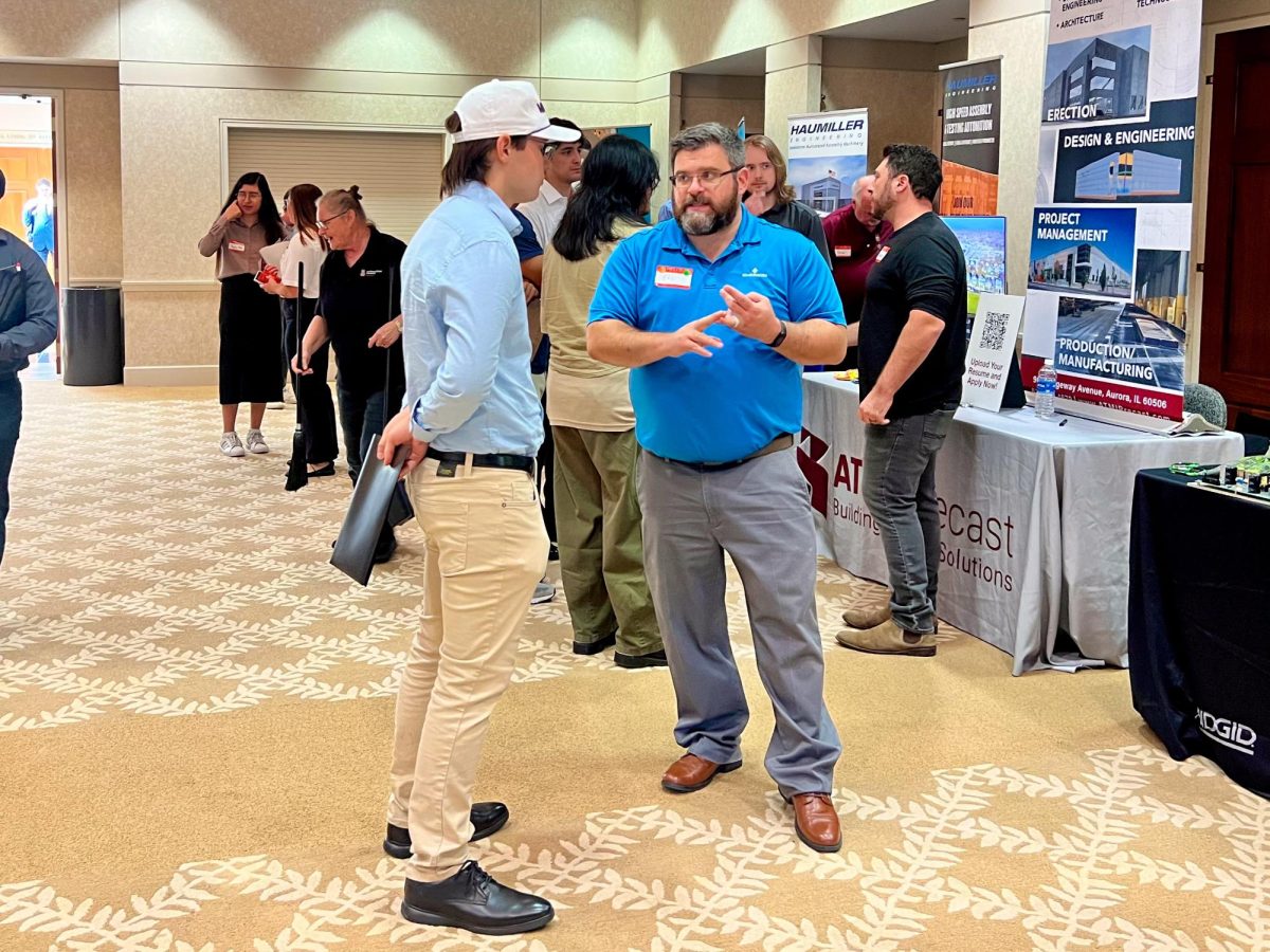 Evan Hammons, a junior electrical engineering major, (left) and Eric Williams, Emerson electrical engineering manager, (right) converse on Tuesday during College of Engineering and Engineering Technology Job and Internship Fair. TheCEET Job and Internship Fair was attended by 40 different companies. (Sofia Howell | Northern Star) 