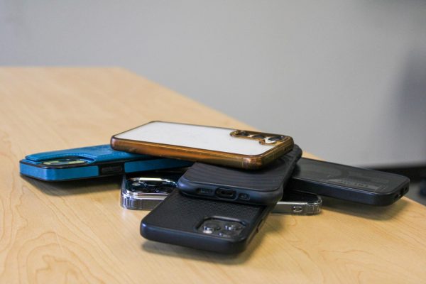 A pile of phones sits stacked on a desk. Opinion Columnist Habiba Kamel believes that phones should be used in school to keep people safe from school shootings.  (Northern Star File Photo) 