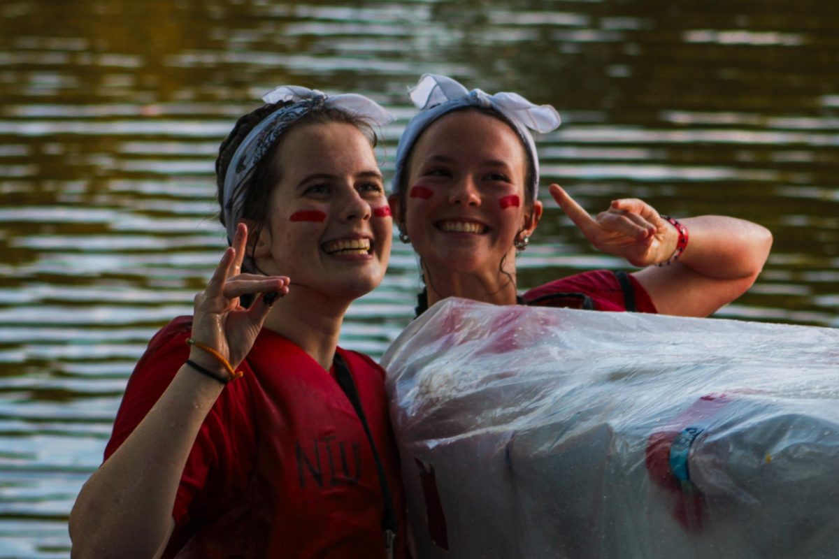 Participants of the Recycled Boat Race Emmeline Sovinski (left) and Kendall Wills smile and make the huskie hand sign on Sept. 30 during the Recycled Boat Race at the East Lagoon. The Recycled Boat Race was held as a part of NIU’s 118th Homecoming Week. (Ethan Rodriguez | Northern Star)