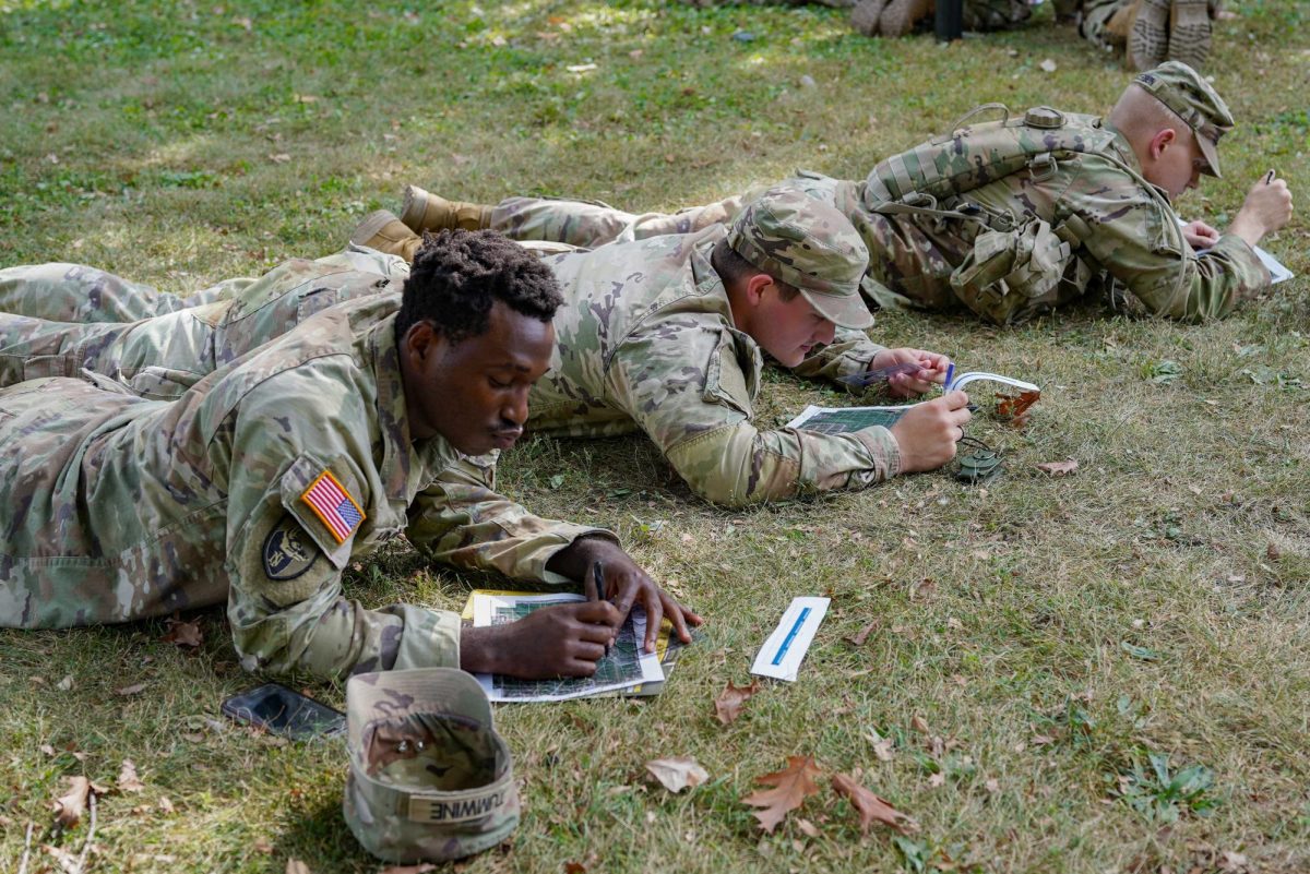 Junior history majors Ethan Patterson (from top), Liam Keller, and junior computer science major Tuwine Kevin lay side-by-side working on their land navigation training on Oct. 2 near the East Lagoon. NIU students enlisted in the National Guard are activated along with students from other Illinois State schools by order from the Trump Administration. (Andrew Young | Northern Star)