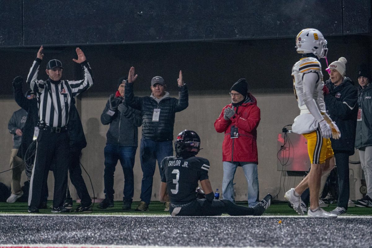 Field judge Cleophas Miller, left, raises his arms signaling a touchdown as NIU redshirt freshman wide receiver Rickey Taylor Jr. (3) sits on the ground after catching an 18-yard touchdown pass in the fourth quarter of a football game against Western Michigan University on Tuesday at Huskie Stadium in DeKalb. Taylor's catch marked the first touchdown of his college career. (Northern Star file photo)