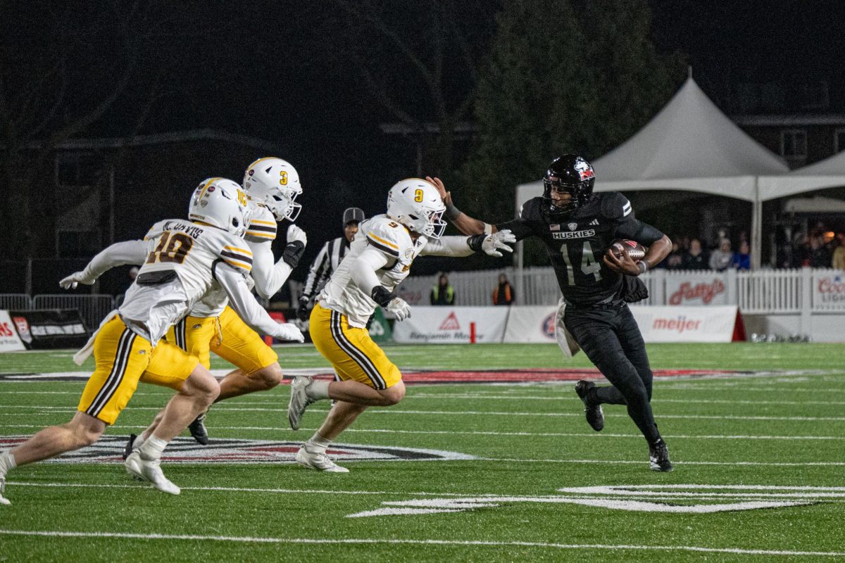 NIU football redshirt junior quarterback Jalen Macon (14) stiff arms a Western Michigan University defender on Tuesday at Huskie Stadium. The Huskies fell to the Broncos by a score of 35-19. (Totus Tuus Keely | Northern Star) 