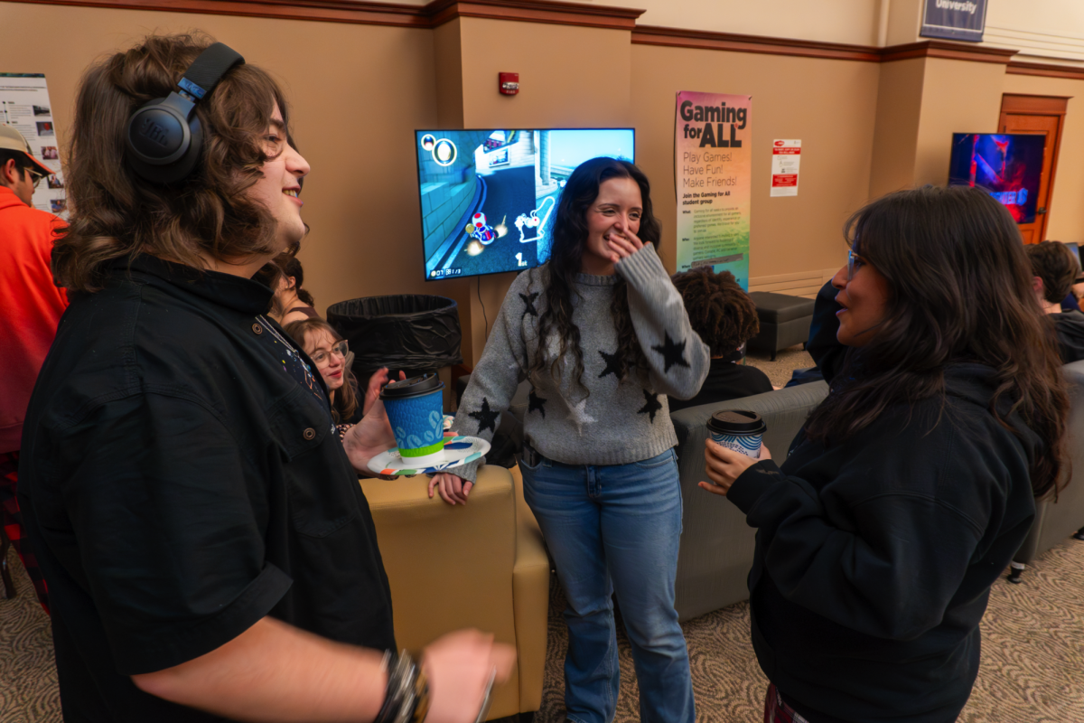 Mikayla Ahern (middle) talks with two of the attendees while enjoying hot cocoa. The Ultimate Cozy Gaming Night was organized by NIU Esports, Huskie Gaming and Gaming for All and encouraged visitors to enjoy gaming with other members of their community. (Courtesy of NIU Esports)