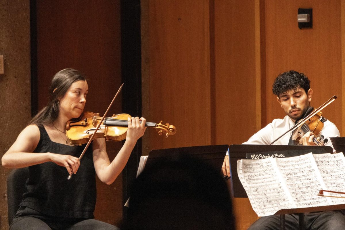 Sally Waterhouse (left) and Javier Polania play on their violins on Nov. 24 in the Recital Hall in the Music Building. The performance was held between 6 p.m. and 7 p.m.  (Grace Kilbreath | Northern Star)