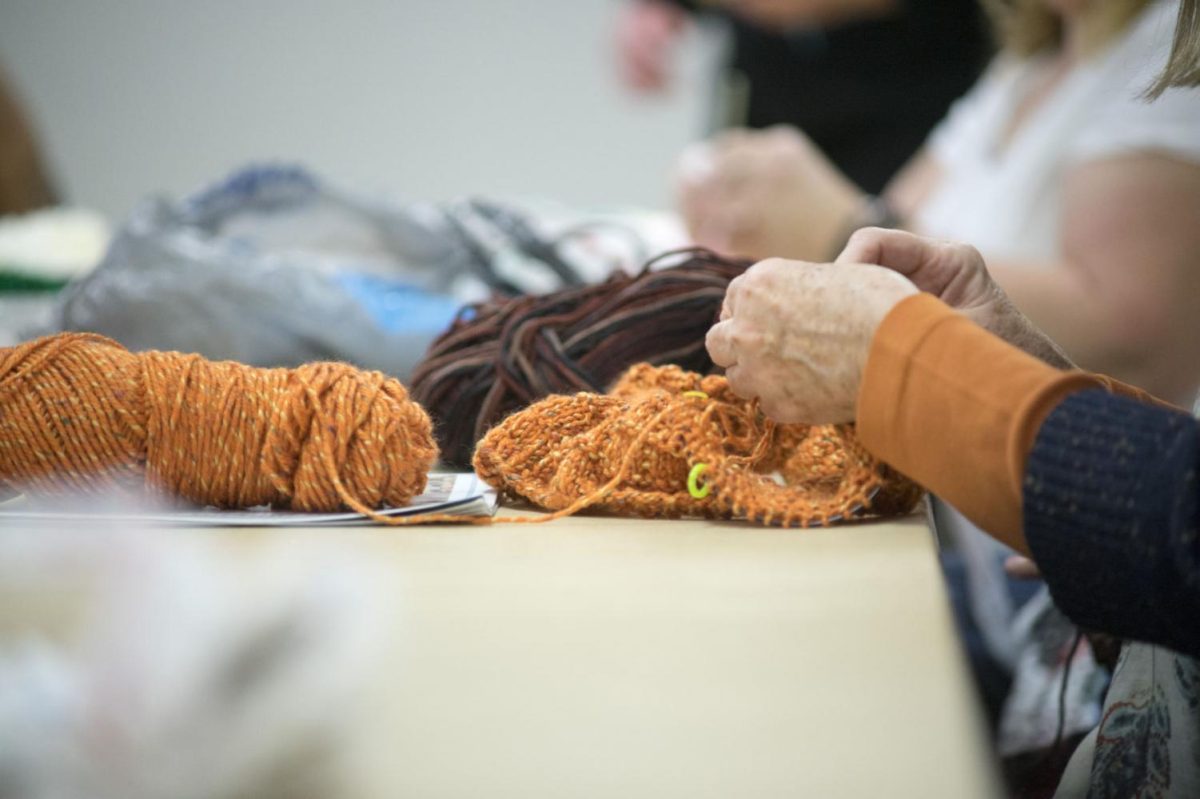 A group of people sit knitting at a table. The NIU Scholarly Stitch Circle event will be from 4 p.m. to 5 p.m. Thursday as well as on Feb. 26 and April 2. (Northern Star File Photo)