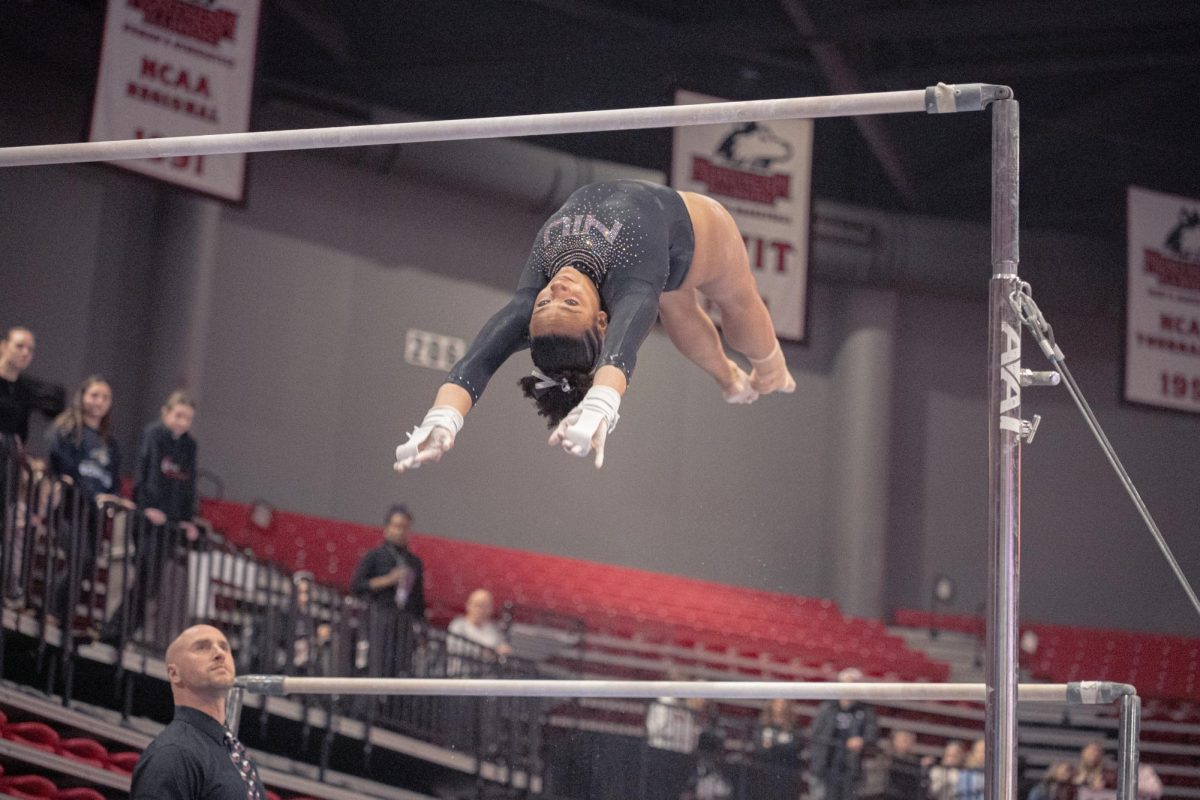 NIU gymnastics freshman Deziray Boykin launches to the other bar during the meet against Ball State University on Saturday in the Convocation Center. The uneven bars was NIU’s lowest performing routine with a score of 45.800, 2.5 points less than their third lowest score. (Totus Tuus Keely | Northern Star)