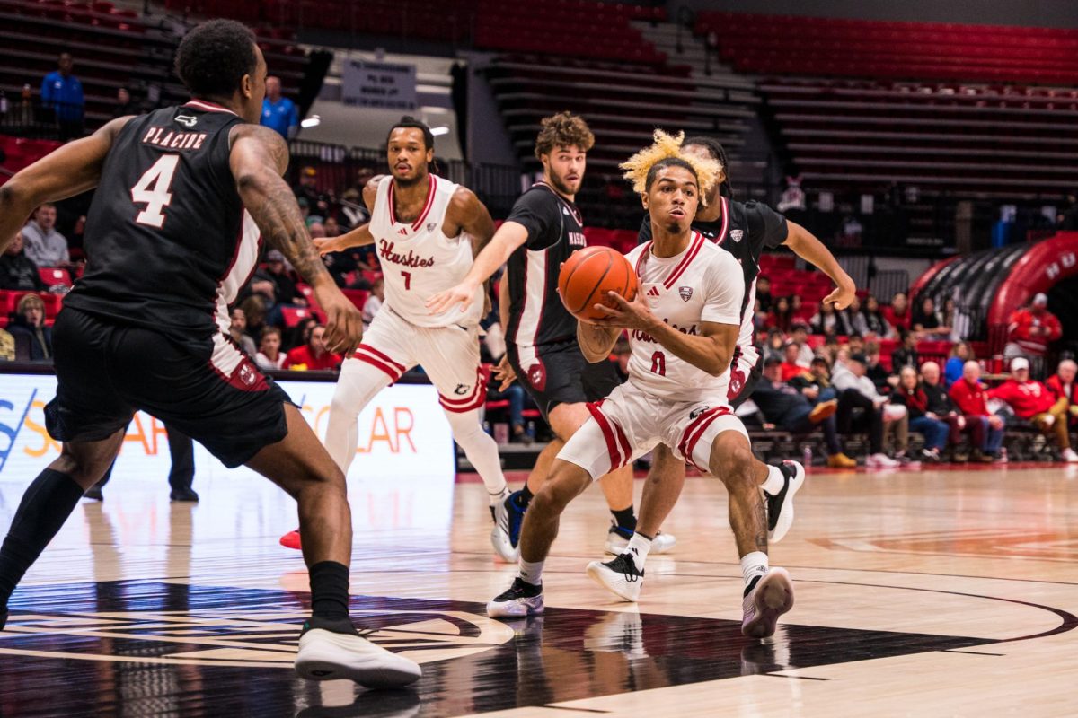 NIU sophomore guard Gianni Cobb (0) looks to pass against University of Massachusetts graduate student guard Isaiah Placide (4) during the first half of a basketball game on Jan. 17 inside the Convocation Center in DeKalb. Cobb led the Huskies with 11 points in Saturday's 58-53 loss to Ball State. (Eric McGill | Northern Star)