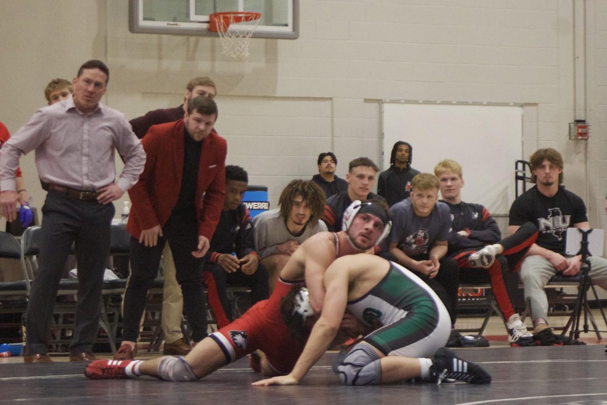 NIU wrestling redshirt sophomore Collin Arch holds Ohio University redshirt junior Paul Woo in a headlock while NIU wrestlers and coaches watch intently. Arch lost in the first round of sudden victory 4-1 by decision. (Sofia Howell | Northern Star)