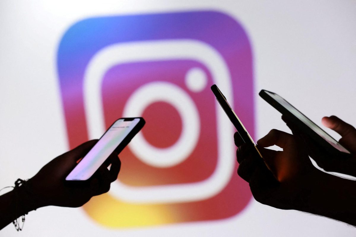 Teenagers pose for a photo while holding smartphones in front of the Instagram logo. Opinion Columnist Habiba Kamel believes social media is making genuine romance hard to come by. (REUTERS | Dado Ruvic)