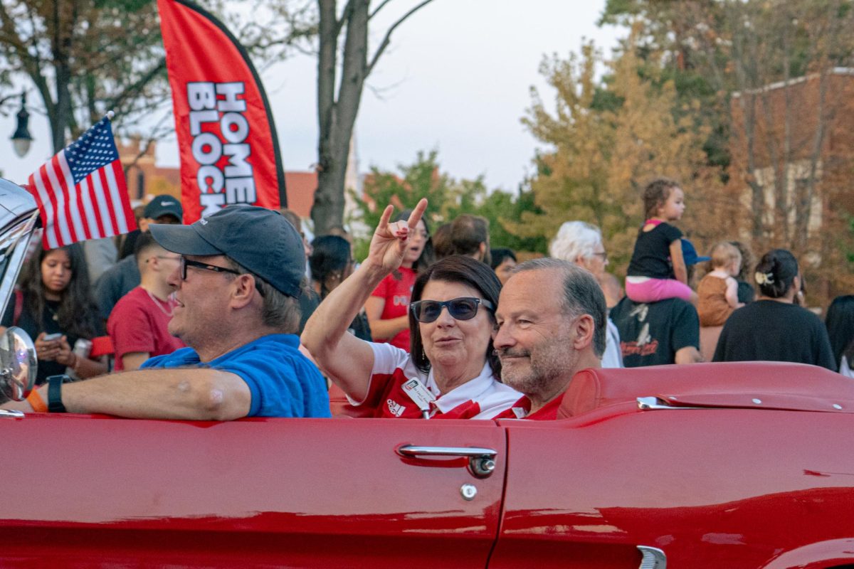 NIU President Lisa Freeman (center) raises the Huskie hand sign from a car in the Homecoming Block Party parade on Oct. 2. Lisa Freeman began as NIU’s president seven years ago after serving in administrative roles at Kansas State University and NIU. (Totus Tuus Keely | Northern Star)