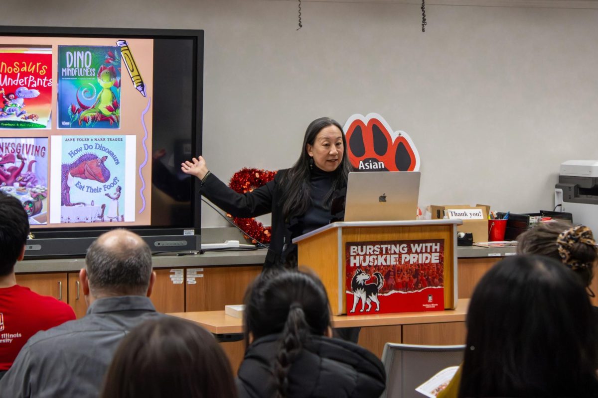 Karen Su, an author of several children's books, points at the abundance of dinosaur-themed children’s books during the “Kids Know More About Dinosaurs Than About Asian Americans” event on Tuesday in the Asian American Resource Center. Su emphasized the importance of representation in children’s books. (Ethan Rodriguez | Northern Star)