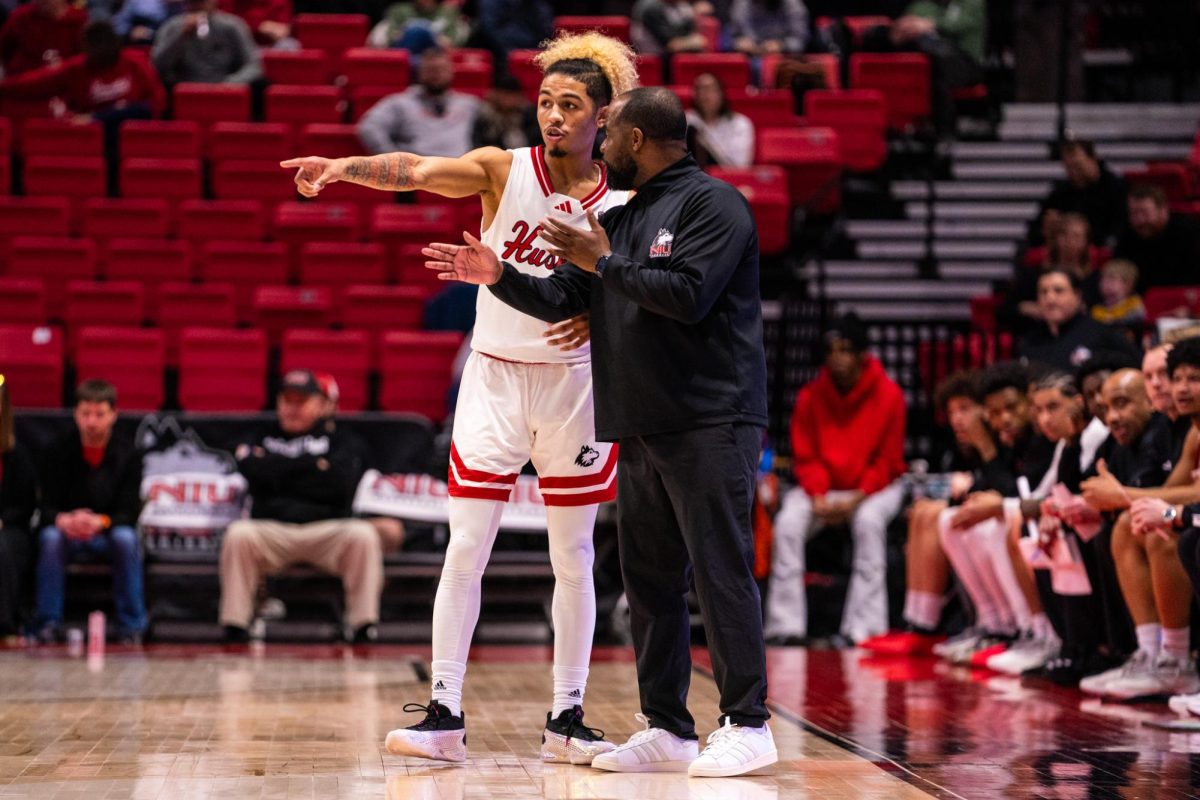 NIU men’s basketball sophomore guard Gianni Cobb talks to head coach Rason Burno early in the first half against Ball State University on Saturday in the Convocation Center. The Huskies lost 79-43 to the Cardinals, their largest loss this season. (Eric McGill | Northern Star)