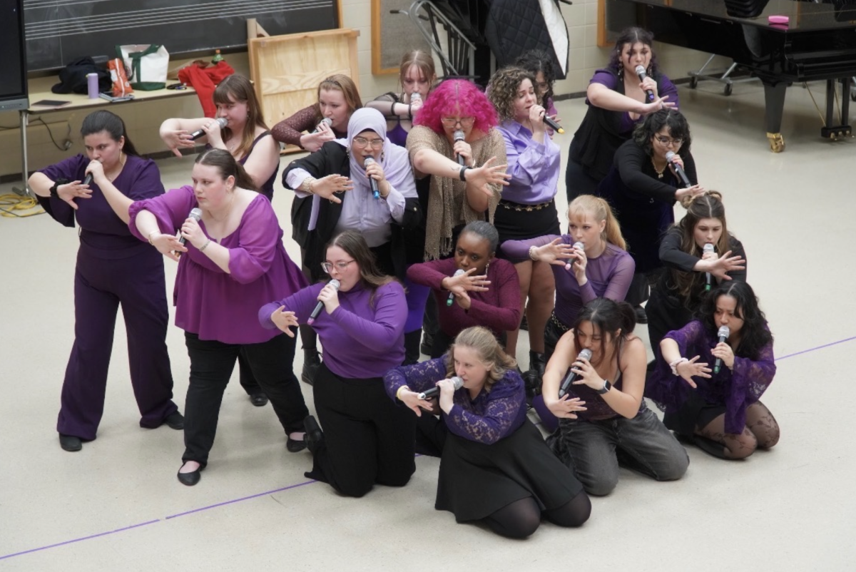 Members of NIU’s all-female a cappella group, the Harmelodics, perform dynamic choreography while singing into handheld microphones during a dress rehearsal performance. The Harmelodics competed in the ICCA Great Lakes Quarterfinal on Saturday at Illinois State University, delivering a high-energy four-song medley but did not advance to the semifinal round. (Courtesy of the Harmelodics)