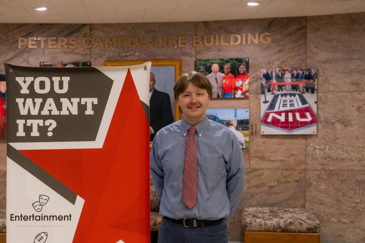 Totus Tuus Keely, a junior mechatronics major, poses next to a Northern Star banner. On Thursday, the Northern Star elected current Photo Editor Totus Tuus Keely as their fall 2026 editor in chief. (Diego Martinez | Northern Star)