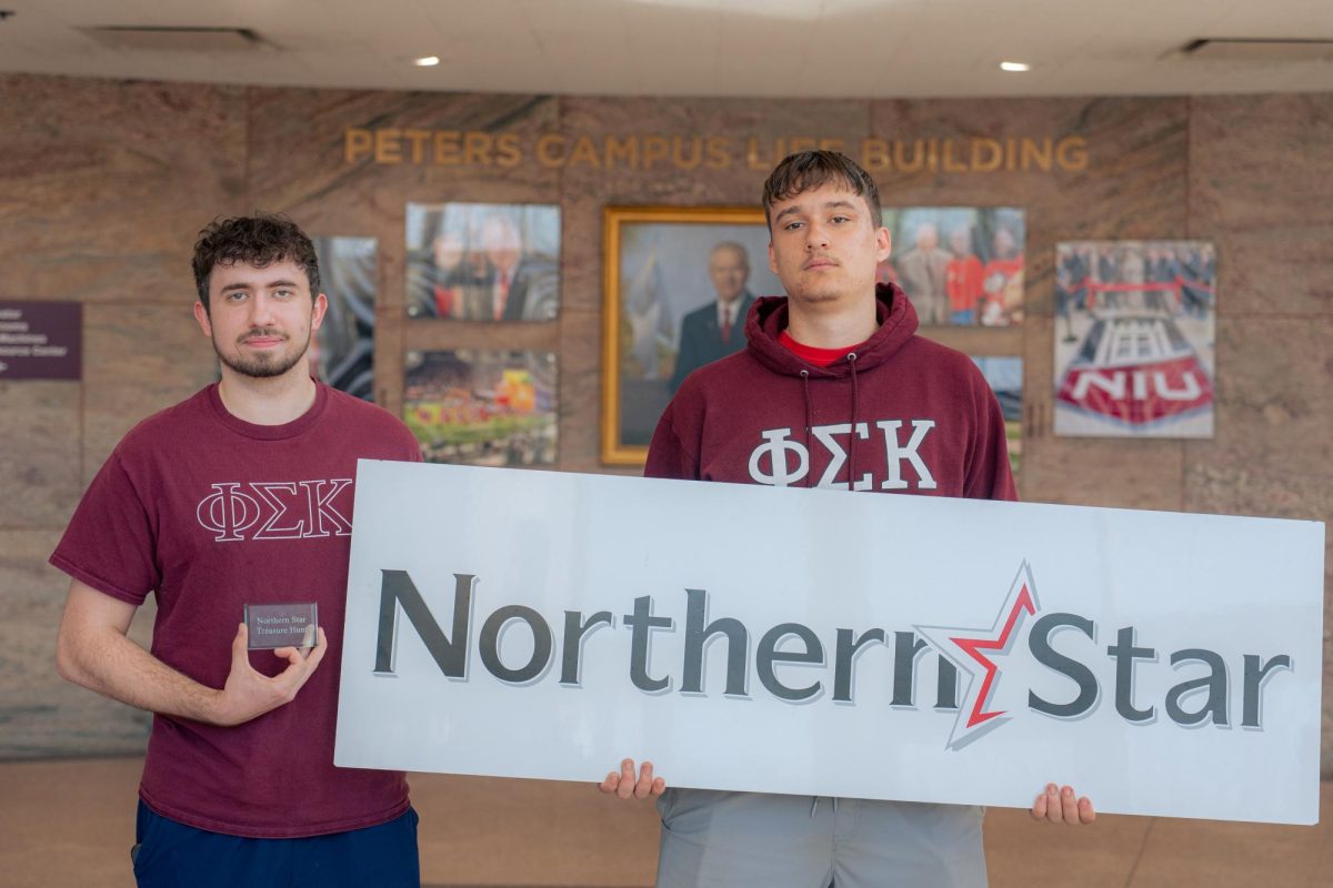 Senior business management major Mason Einsiedel (left) poses with the Northern Star paperweight next to junior mechanical engineering major Paul Samsonek on Thursday in Peters Campus Life Building. Einsiedel found the paperweight Wednesday evening after deciphering the clues with Samsonek. (Totus Tuus Keely | Northern Star)