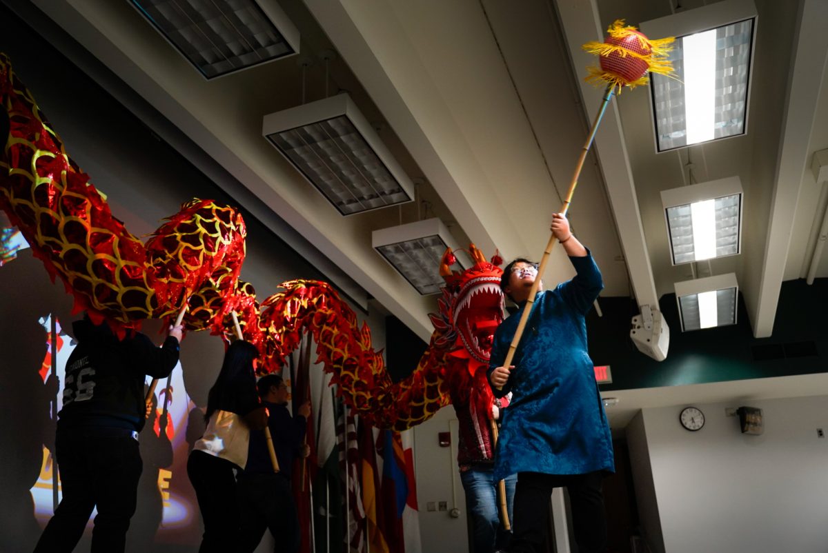 Ryan Le, a junior psychology major, leads a lion dance during the AARC showcase held Tuesday in Wirtz Hall. The dance is traditionally performed to ward off bad omens and bring prosperity, according to presenters. (Ty McWilliams | Northern Star)