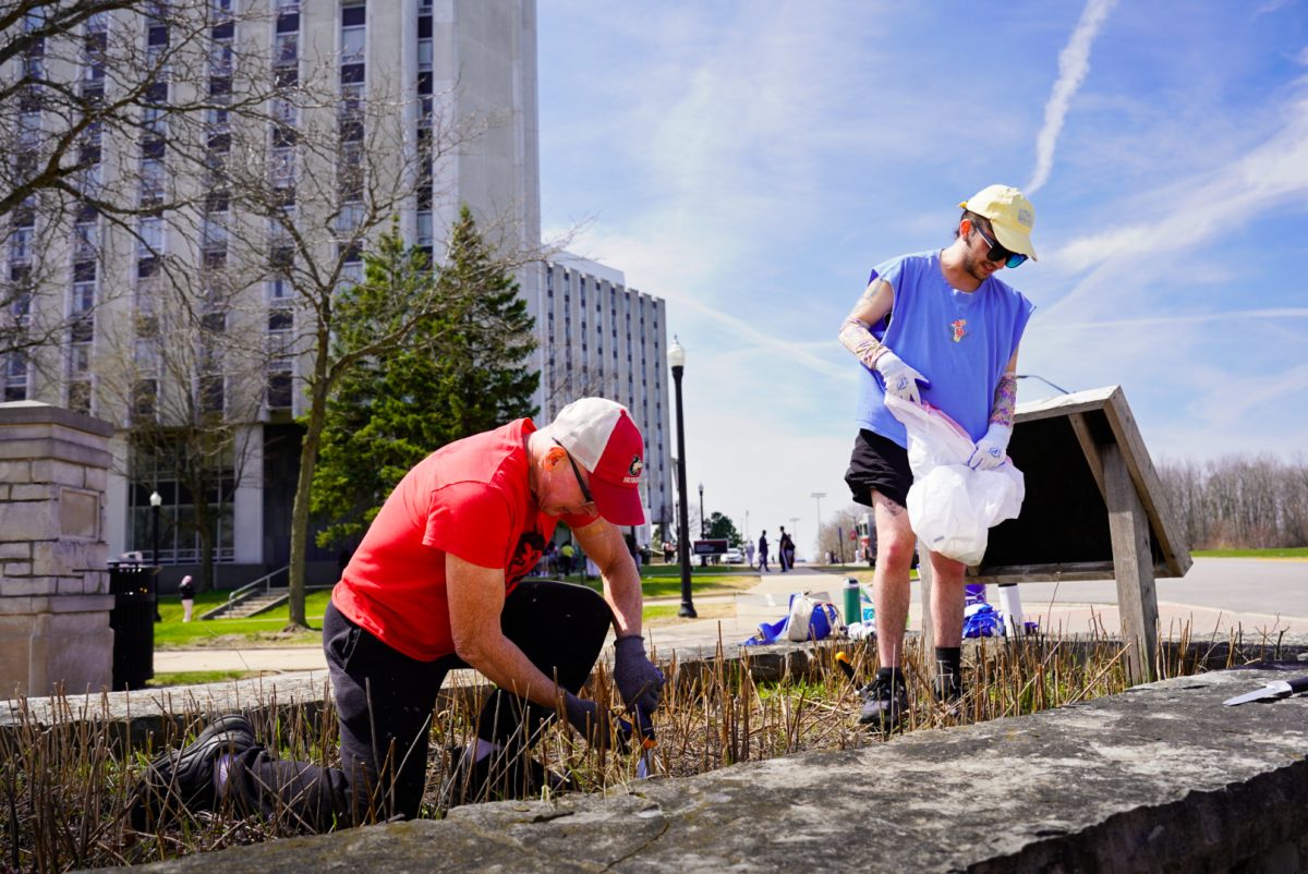 Bryan Nigbor (left), a DeKalb resident, and Oliver Myers, a second-year public administration graduate student, clear weeds from the plant bed Thursday outside of Stevenson Towers. The cleanup was held from 1:30 p.m. to 3:30 p.m. (Ty McWilliams | Northern Star)