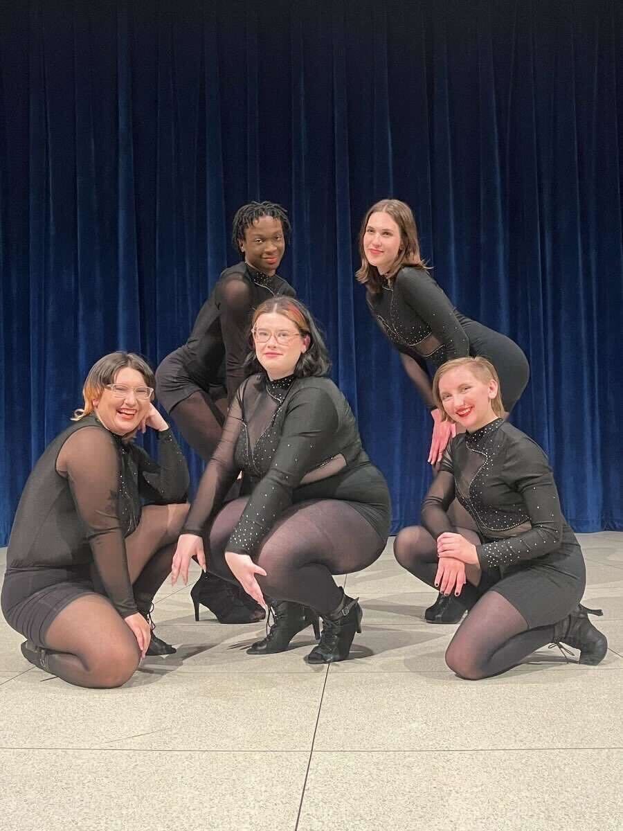 Members of the NIU Burlesque Dance Team pose together in coordinated black performance outfits during a rehearsal. The team is preparing for its upcoming spring showcase on April 25 in the Carl Sandburg Auditorium at the Holmes Student Center, highlighting burlesque dance’s theatrical, expressive style and its focus on confidence and creativity. (Courtesy of the Burlesque Dance Team)