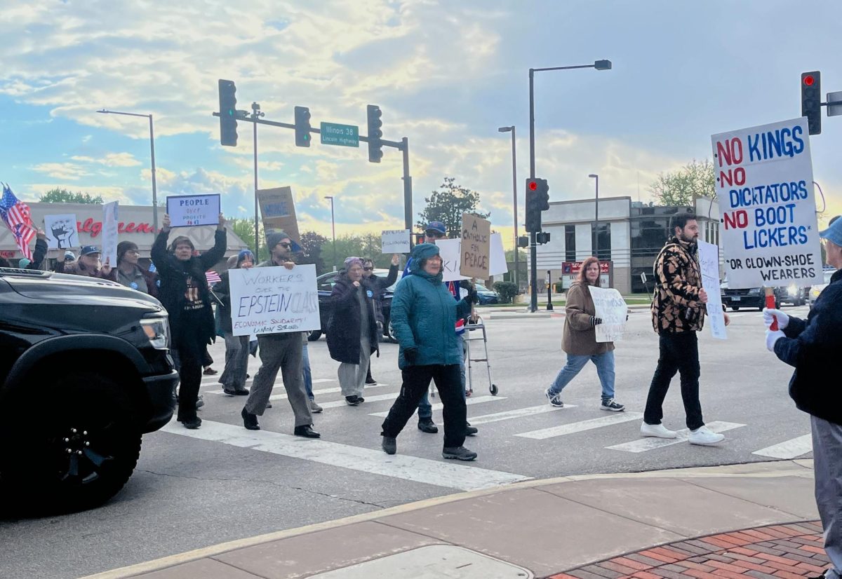 Protestors march down Lincoln highway and North 1 St. holding signs. Around 90 people rallied calling on policymakers in Springfield and Washington, D.C. to tax the wealthy and deliver on promised resources to Illinois public schools. (Kiana Clingon | Northern Star)
